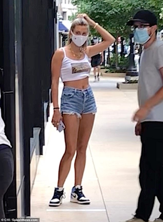 Hailey Bieber showcases her taut midriff and slender pins in a white